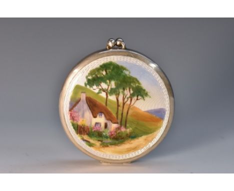 A George V silver and enamel circular compact, hinged cover decorated in polychrome with a thatched cottage, gilt interior, 5