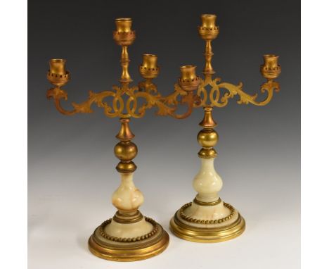 A pair of 19th century Midland alabaster and gilt metal three-light candelabra, waisted sconces, engraved leafy scroll branch