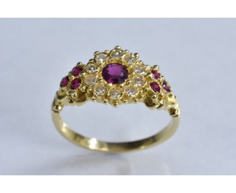 A ruby and diamond cluster ring, central round cut red ruby, surrounded by a band of ten round old brilliant cut diamonds, be