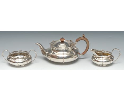 A George V silver three piece melon-fluted tea service, comprising teapot, milk jug and sugar basin, each with raised pierced
