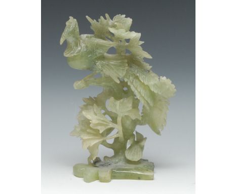 A Chinese green jade group, carved with a phoenix perched in foliage, 25cm high