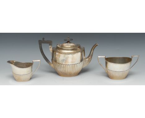 An Edwardian silver three-piece half fluted oval tea service, comprising teapot, milk jug and two handled sugar basin, angula