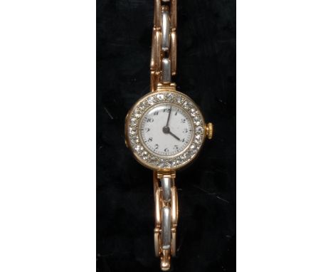 A George V lady's diamond set 18ct gold wristwatch, cream enamel dial, Arabic numerals, minute track, dial surrounded by a ba