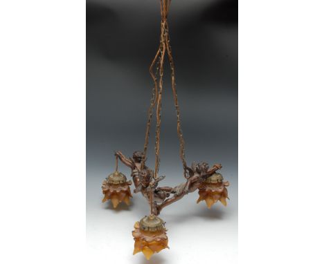 An Art Nouveau design brown patinated ceiling lamp, cast as three putti supporting amber flashed glass shades, fitted as an e