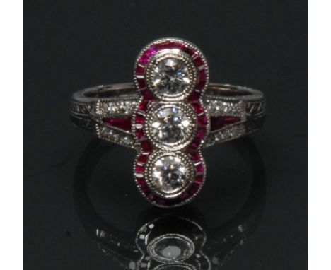 An Art Deco style ruby and diamond cluster ring, three liner round brilliant cut diamonds, surrounded by a band of trapezoid 