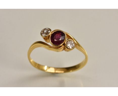 A diamond and ruby twisting trilogy ring, central oval cut red ruby approx 0.50ct, flanked by a smaller round brilliant cut d