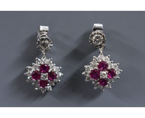 A pair of ruby and diamond cluster earrings, each inset with four round cut rubies and eighteen round brilliant cut diamonds,