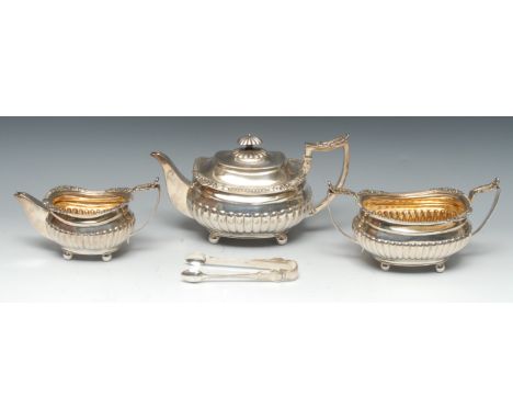 A George III silver three piece half-fluted boat shaped tea service, comprising teapot, milk jug and sugar basin, acanthus-ca