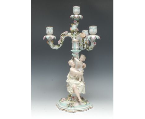 A Meissen figural four-light, three branch candlestick, the scroll arms encrusted with flowers and foliage, the column with c