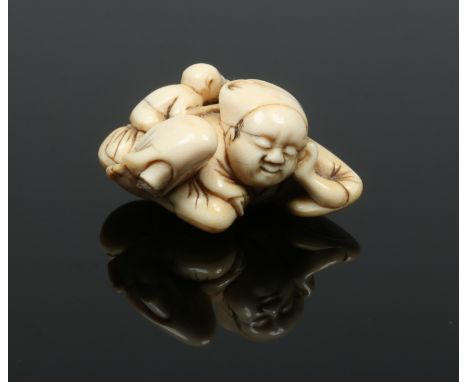 A Japanese Edo period carved ivory netsuke formed as a sleeping man with a monkey stealing nuts from a basket behind, 5.25cm 