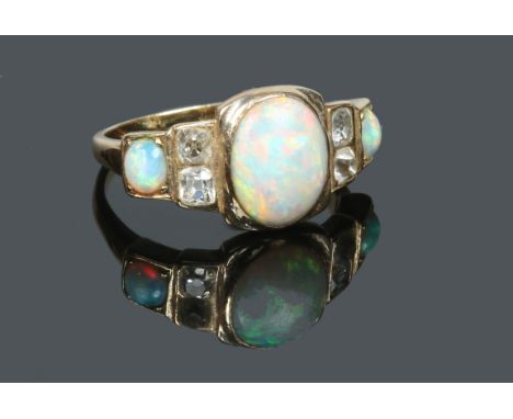 A yellow metal Art Deco style ring. Set with an ovoid opal and to each shoulder with a further opal and pair of diamonds. Siz