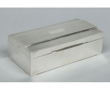 An Art Deco silver cigarette box. With stepped cover having engine turned engraving. Assayed Birmingham 1939, 18cm wide. Cond