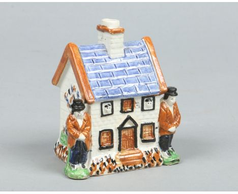 An early 20th century prattware money box formed as a cottage with a pair of figures at each side and coloured in enamels, 12