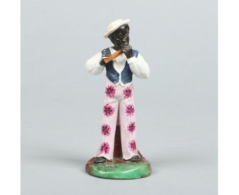 A 19th century Staffordshire porcelain figure. American slavery related, depicting and African-American playing a flute and d