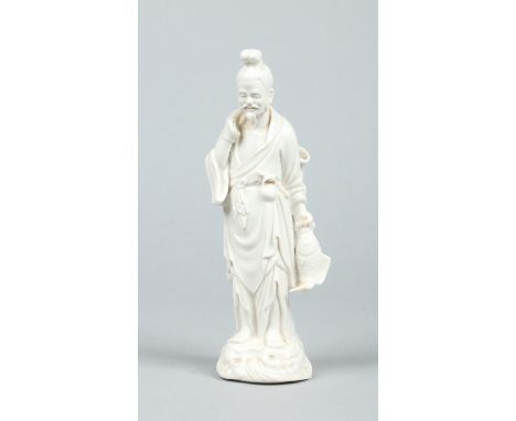 A Chinese blanc de chine figure of a fisherman. Carrying a net over his shoulder and with a fish in his other hand, raised on