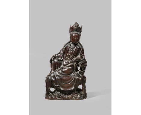 A CHINESE ZITAN FIGURE OF GUANYIN REPUBLIC PERIOD Seated on a rock pedestal in a relaxed pose, wearing long flowing robes, a 