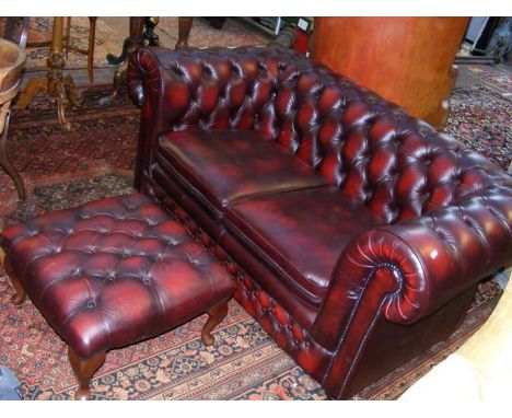 A red leather style two seater sofa with matching square footstool 