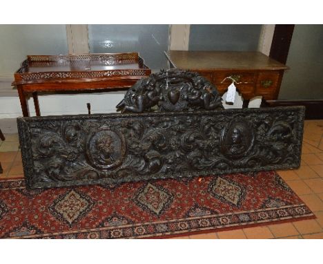A VICTORIAN HEAVILY CARVED OAK PANEL, with cresting in the form of two putti with shield above a foliate carved main section,