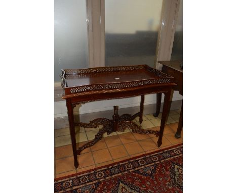 A REPRODUCTION CARVED MAHOGANY CENTRE TABLE, of a wavy form, the pierced gallery top on square tapering legs united by a foli