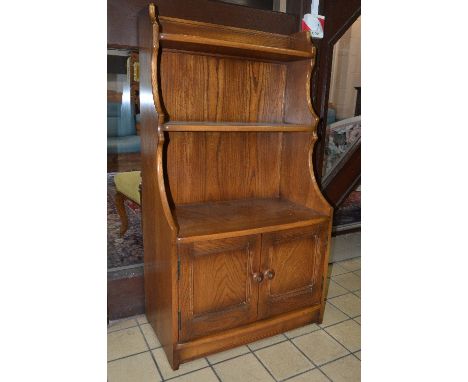 AN ERCOL GOLDEN DAWN WATERFALL BOOKCASE, above double cupboard doors