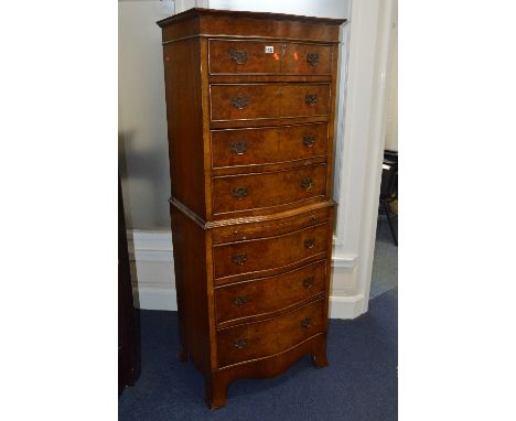 A REPRODUCTION GEORGIAN STYLE BURR WALNUT SERPENTINE CHEST ON CHEST, of seven graduated drawers with brass handles, central d