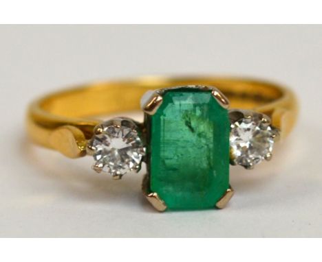 A 22ct yellow gold emerald and diamond ring, the central emerald cut stone flanked by two round cut diamonds, each approx 0.2