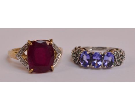 A 9ct yellow gold dress ring set with large faceted ruby coloured stone in claw setting flanked by two chevrons set with tiny