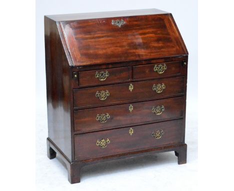 A George III mahogany bureau of small proportions, the fall front enclosing an interior of pigeon holes and drawers above two