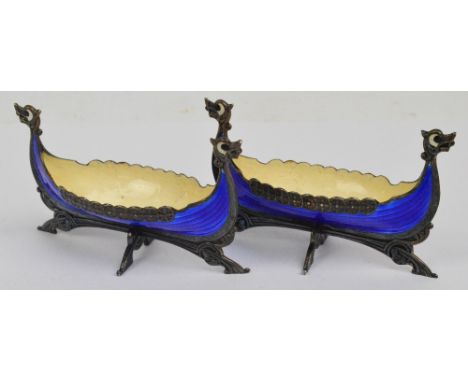 A pair of enamel decorated salts modelled as Viking boats, each with white enamel decoration to the interior and blue enamel 