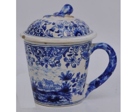 An early 19th century Dutch Delft cup with cover and saucer with moulded fruit finial, overall painted with landscape and wit