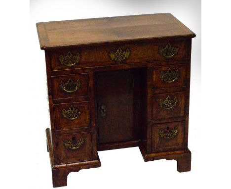 An 18th century and later adapted walnut feather banded kneehole desk, the rounded rectangular top with re-entrant corners ab