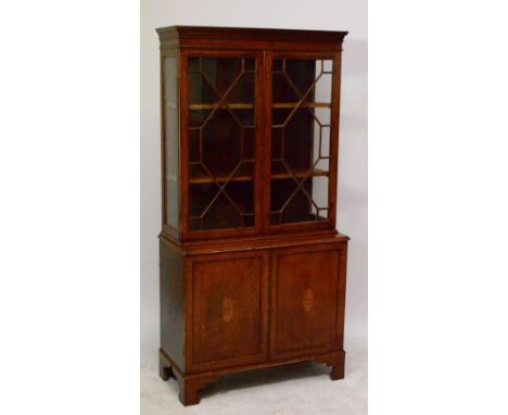 An Edwardian mahogany satinwood inlaid bookcase on cupboard, the upper section with twin astragal glazed doors above a base o