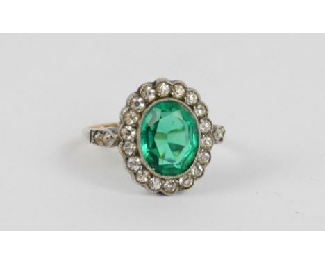 A 9ct yellow gold and silver dress ring with a green paste oval brilliant cut stone surrounded by clear stones, size K/L, app