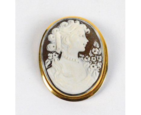 A small oval 18ct yellow gold mounted shell cameo brooch depicting the bust of a lady with flowers with suspension ring, heig