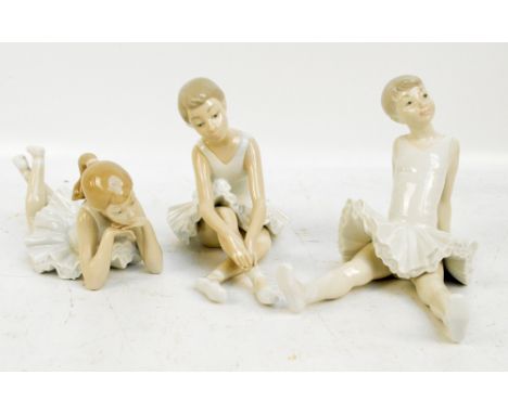 Three Nao ballerina figures, two sitting and one lying.