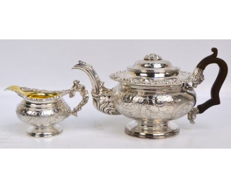 A George IV hallmarked silver teapot of squat globular form with overall engraved foliate and scroll decoration, centred with
