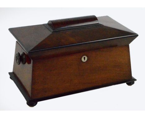 An early 19th century mahogany sarcophagus shaped tea caddy with two circular handles and circular mother-of-pearl escutcheon