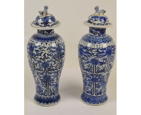 A near pair of 19th century Chinese porcelain vases of baluster form with covers surmounted with Dogs of Fo, painted in under