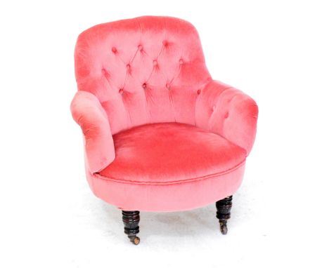 A late Victorian button back upholstered low tub elbow chair raised on ring turned front legs.