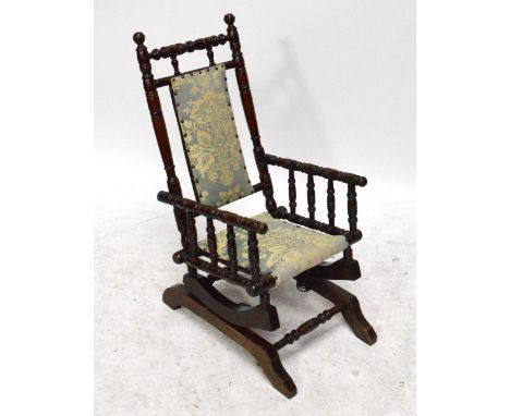 An early 20th century child's upholstered American rocker with ring turned decoration, width 38cm.