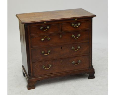 A George III mahogany chest of small proportions, with brushing slide above two short and three long drawers flanked by flute