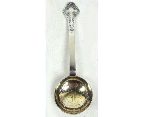 A George V hallmarked silver lace back sifting spoon with circular gilt wash bowl and trifid shaped finial, William Hutton & 
