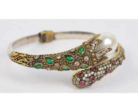 A 925 standard silver and gilt stylised snap bangle set with rubies, pear-shaped emerald coloured stones and clear stones wit