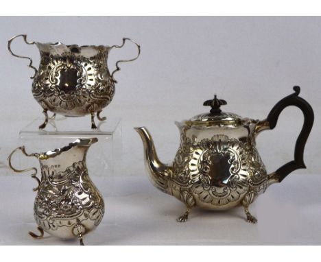 A late Victorian hallmarked silver three piece tea service with bird and foliate scroll embossed decoration and engraved init