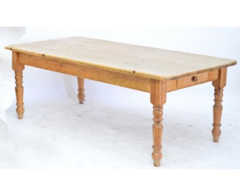 A pine plank top kitchen table with rounded rectangular top above twin frieze drawers raised on ring turned legs to peg feet,