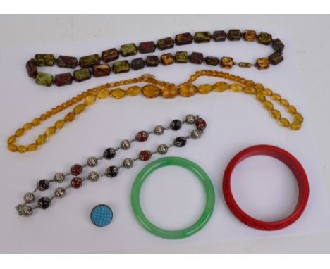 A small group of costume jewellery comprising a green hardstone bangle, a cinnabar effect example, an amber coloured glass fa