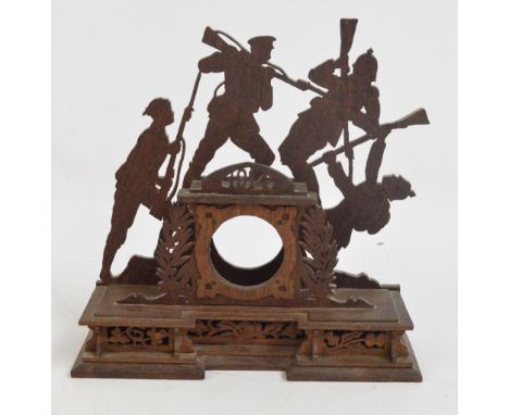A WWI fretwork clock stand, the pierced surround set with four soldiers centred by the clock aperture, beneath a pierced plaq