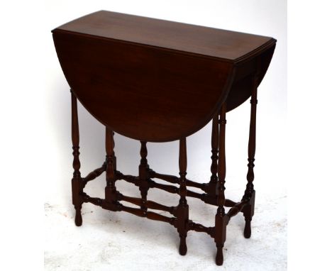 An early 20th century mahogany drop leaf occasional table raised on ring turned and black supports, width 68cm.