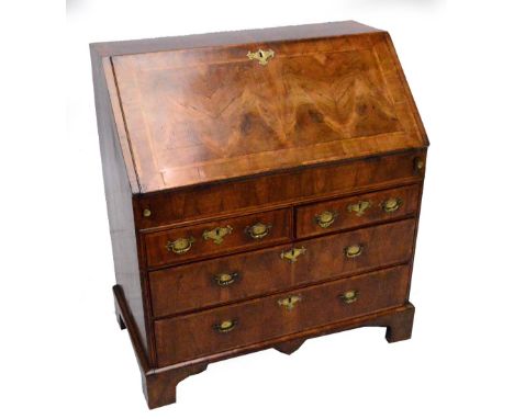 An early 18th century walnut and feather banded bureau, the fall front enclosing interior of shelves and pigeon holes with sl