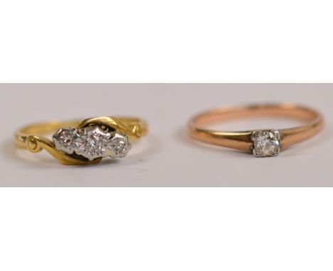 A yellow metal and diamond solitaire ring, stone approx 0.12cts, size M and a further three stone crossover example with illu